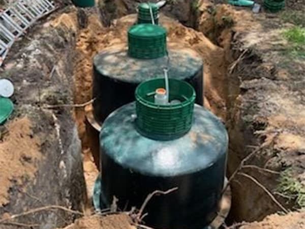 Excavation crew installing septic tanks for property wastewater system upgrade Excavation crew installing septic tanks for property wastewater system upgrade